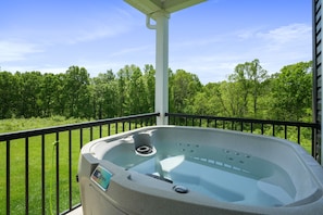 A hot tub on a balcony with a view of a green landscape.