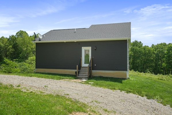 A single-story building with a dark exterior, a white door, and a small set of steps leading to the entrance.