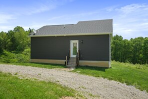 A single-story building with a dark exterior, a white door, and a small set of steps leading to the entrance.
