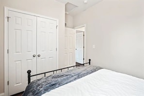 Un dormitorio con cama, puertas dobles blancas y un pasillo.