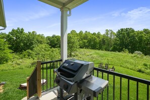 Un barbecue sur un balcon donnant sur un espace verdoyant et des arbres.
