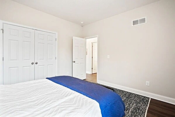 A bedroom with a bed, a wardrobe, and a door leading to another room.