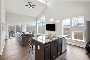 A modern kitchen with a central island, dark cabinetry, and pendant lighting.