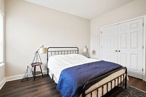 Un dormitorio con cama, escritorio, silla, lámpara y armario.