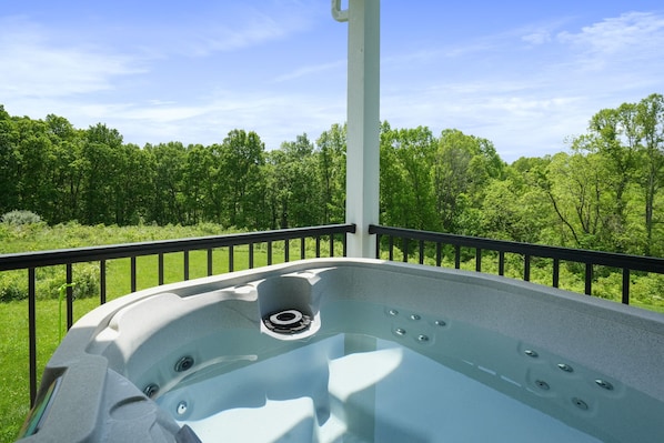 A hot tub with a clear view of a lush green landscape and a blue sky.