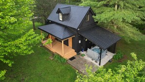 En toetages hytte med en overdækket veranda, jacuzzi og en lille terrasse.
