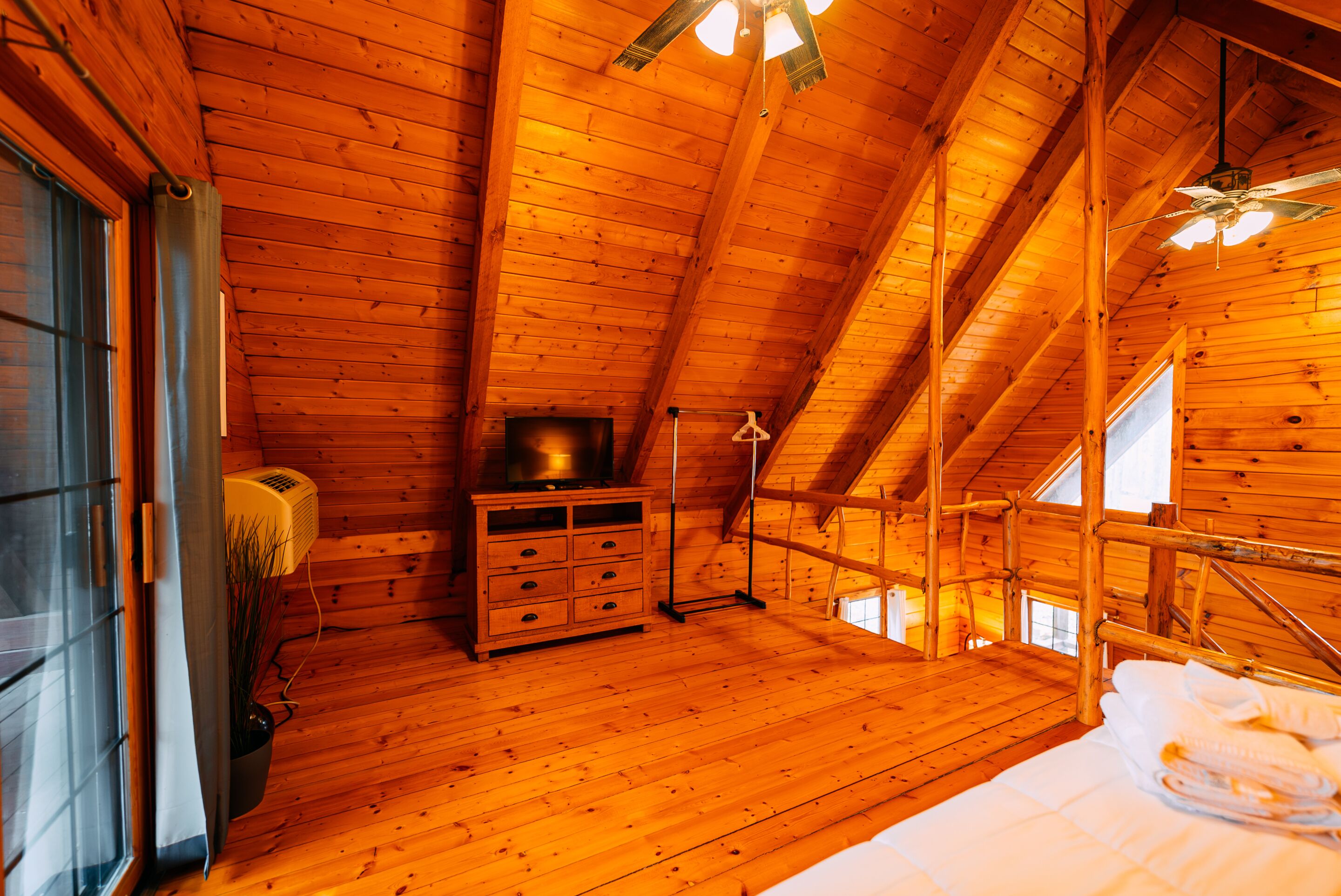 Un interior de madera con una cama, un aparador y un ventilador de techo.