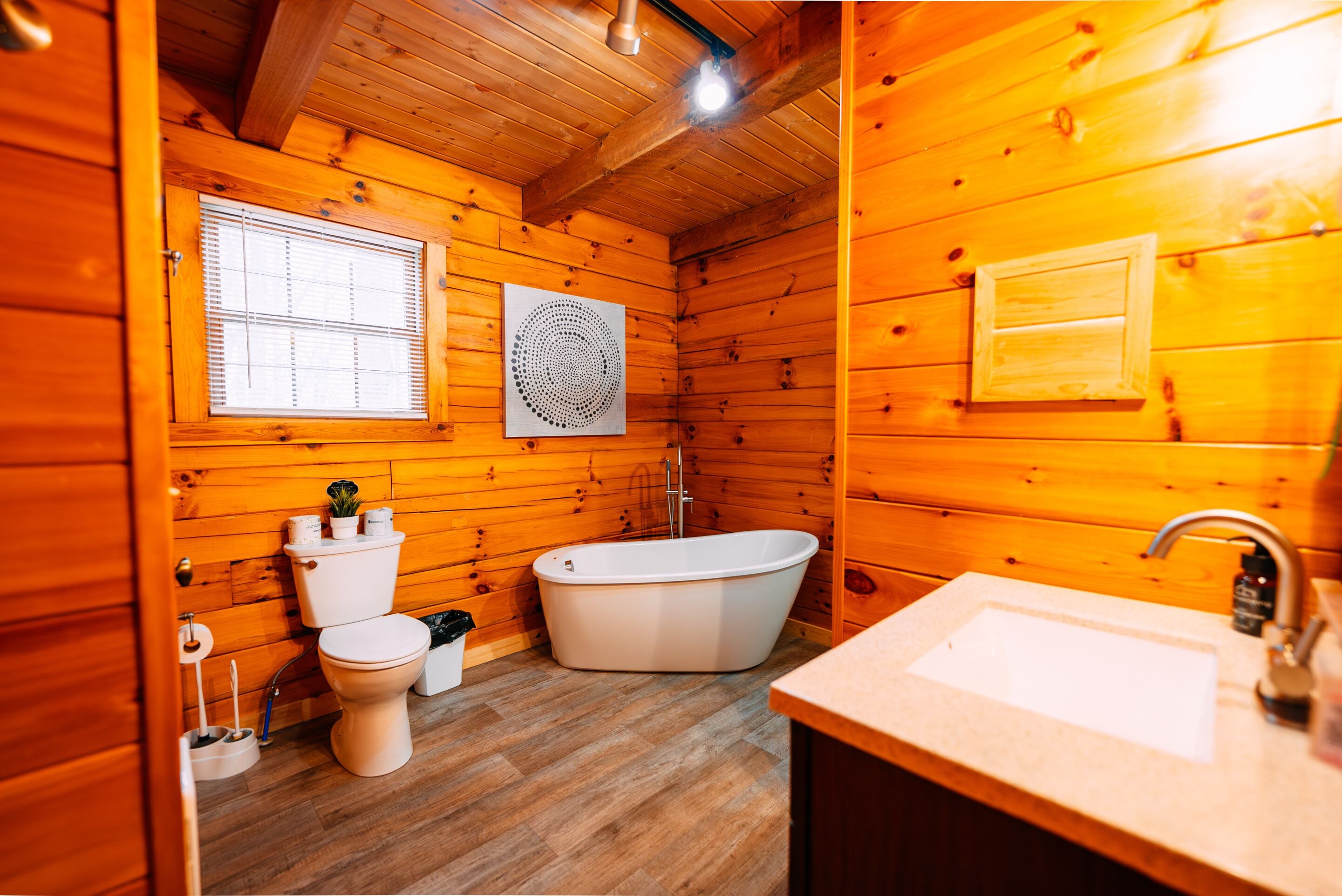 Een houten badkamer met een toilet, bad en wastafel.
