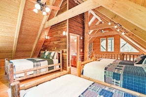 A cozy attic bedroom with two beds, wooden beams, and a sloped ceiling.