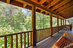 A wooden deck with a wooden bench and a railing overlooking a forested area. - Grizzly Ridge | Hocking Hills, Pool, Hot Tub (Logan)