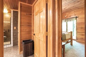 Ein Holzblockhaus-Interieur mit Bad, Bett und Mülleimer.