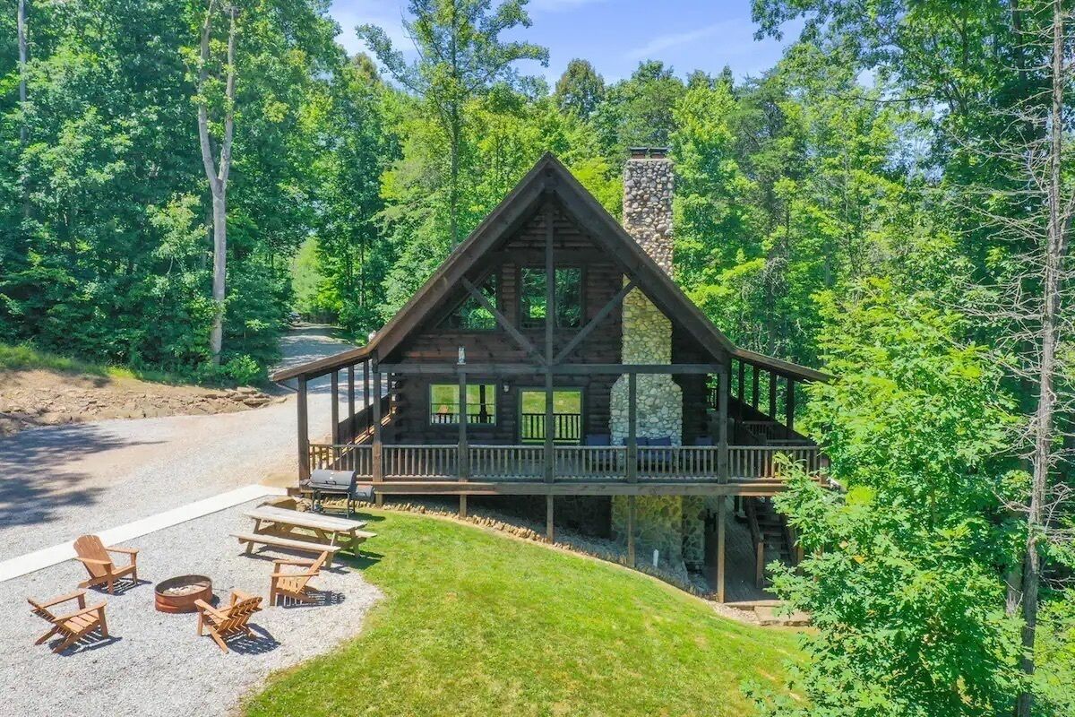 Une cabane dotée d’une cheminée en pierre, d’une terrasse en bois et d’un espace salon extérieur.