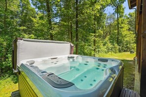 Ein Outdoor-Whirlpool mit Deckel, umgeben von einem bewaldeten Gebiet.