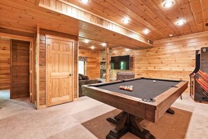 A wooden-paneled room with a pool table, a television, and a fireplace. - Grizzly Ridge | Hocking Hills, Pool, Hot Tub (Logan)