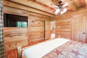 Ein schlichtes Schlafzimmer im Chalet-Stil mit einem Bett, einem Deckenventilator und einem Fenster.