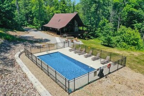 A rectangular swimming pool with a black metal fence, surrounded by a gravel area.