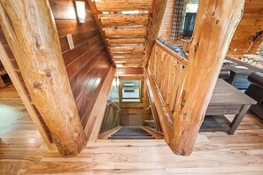 Eine Holztreppe führt zu einer unteren Ebene, umgeben von Holzwänden und Holzdielen.