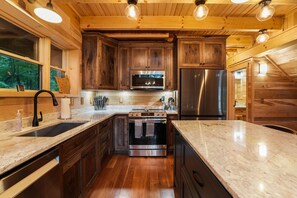 Een moderne keuken met houten kastjes, roestvrijstalen apparatuur en een marmeren aanrecht.