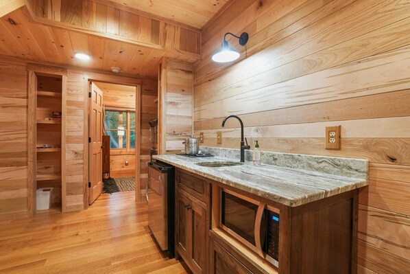 A wooden interior with a kitchen area featuring a sink, countertop, and built-in oven.