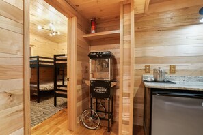 L’intérieur d’un chalet en bois est aménagé avec des lits superposés, un chariot à pop-corn et un coin cuisine.