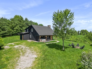 A two-story log cabin with a dark roof, a porch with outdoor seating, and a stone fireplace. - Hilltop Hideaway | Hocking Hills, 16 Acres (McArthur)