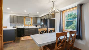 A modern kitchen with grey cabinets, a black refrigerator, and a dining table with wooden chairs.