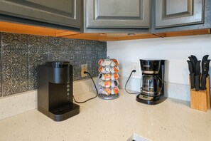 A kitchen with a coffee maker, a coffee pod holder, and a knife block.