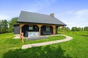 A small, single-story building with a covered porch and a grill area.