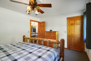 A bedroom with a bed, wooden wardrobe, and a ceiling fan.