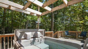 Poreallas puisen pergola-katoksen alla, jonka yhteydessä on puinen terassi ja tuoleja.
