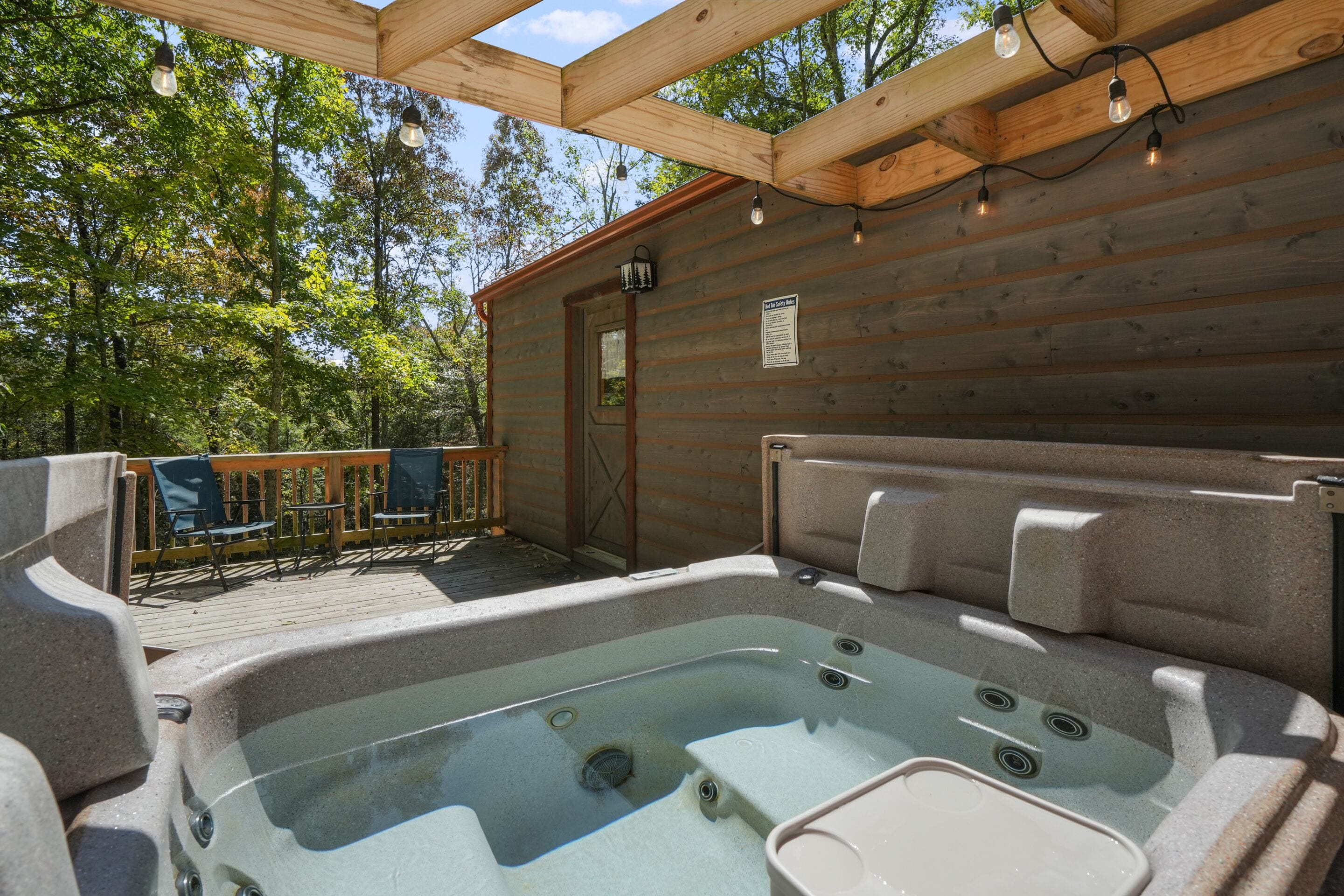 A wooden cabin with a hot tub and outdoor seating.