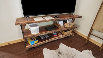 A wooden entertainment unit with a television, books, and storage baskets.