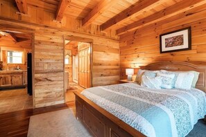 Une chambre dans une cabane en bois, avec un lit, une table de chevet et un tableau encadré au mur.