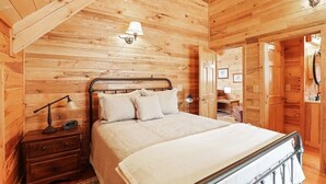 Ein gemütlicher Holzraum mit Bett, Nachttisch, Lampe und Kleiderschrank.