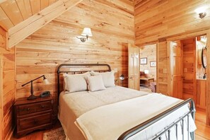 A cozy wooden room with a bed, a nightstand, a lamp, and a wardrobe.