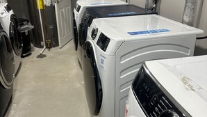 A laundry room with two front-loading washers and dryers, a water heater, and a door leading to another room. - Almira Properties Unit 3 (Providence)