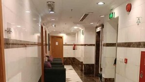 Un couloir d’hôtel avec un sol à motifs à carreaux, un espace détente et un détecteur d’incendie sur le mur.