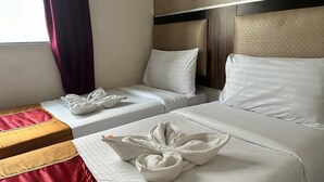 Une chambre d’hôtel avec deux lits, chacun agrémenté de draps et d’oreillers blancs, et un couvre-lit rouge et jaune sur le lit situé à gauche.