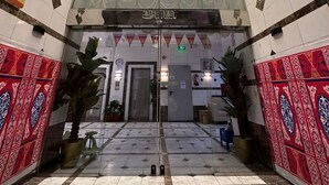 L’entrée d’un hôtel avec une porte en verre, un sol carrelé et des murs décorés de motifs.