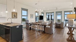 A modern kitchen with a central island, dining area with chairs, and a large window with a view.