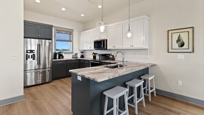 A modern kitchen with stainless steel appliances, white cabinetry, and a central island with bar stools.
