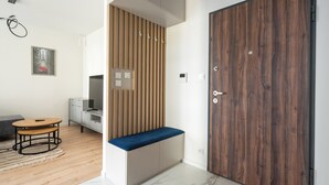 Un interior moderno con un banco de madera, un armario grande y un comedor con mesa y sillas.