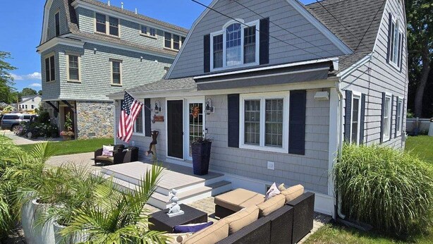 A two-story house with a porch, a flag, and outdoor seating. - Charming year-round beach home in Indian Town, Old Saybrook (Old Saybrook)