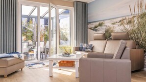 A modern living room with a sofa, armchair, and coffee table. - Vacation home Usedom-Idyll - Modern vacation home with beach chair - only 700 m to the beach (Loddin)