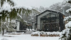 Een modern huis met een groot raam en een stenen fundering.