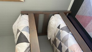 Una habitación con una cama pegada a la pared, una ventana con vistas y una puerta.