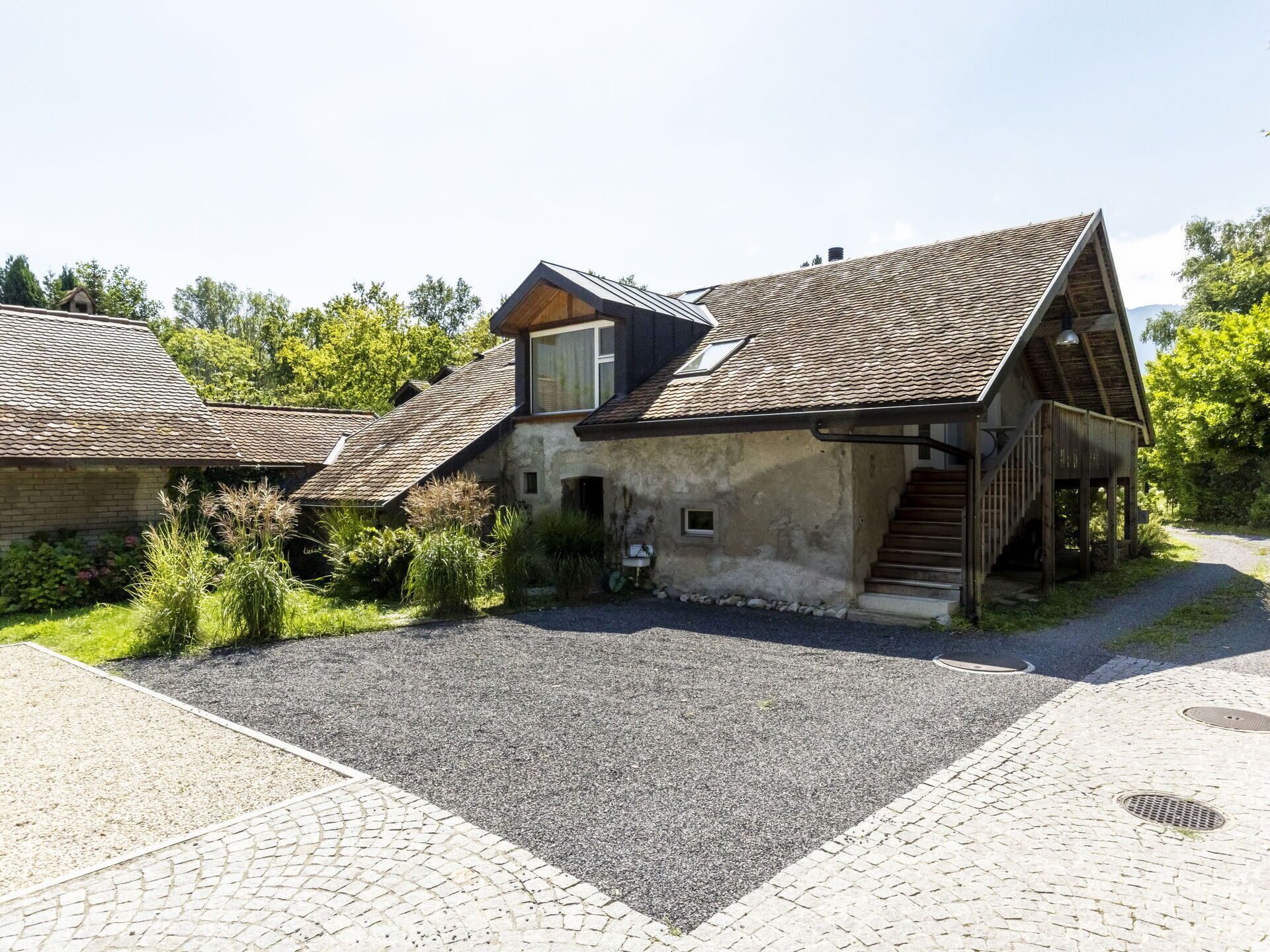 Un bâtiment rustique doté d’un toit en pente, d’une petite fenêtre et d’un escalier menant à une terrasse en bois.
