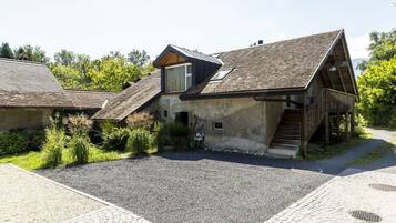 Un bâtiment rustique doté d’un toit en pente, d’une petite fenêtre et d’un escalier menant à une terrasse en bois.