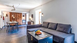 Ein modernes Wohnzimmer mit einer Couch, einem Couchtisch mit Früchten und einem Essbereich mit Stühlen und Tisch.