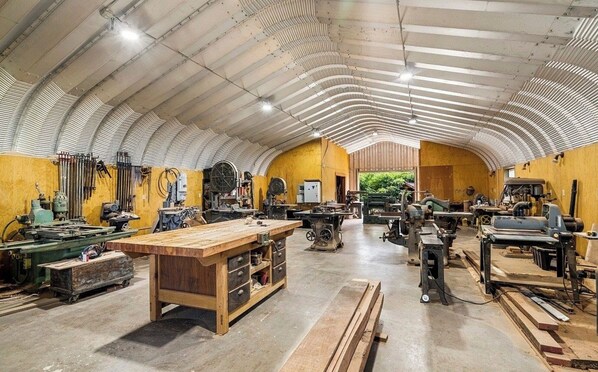 A spacious workshop with large workbenches, various tools, and machinery.